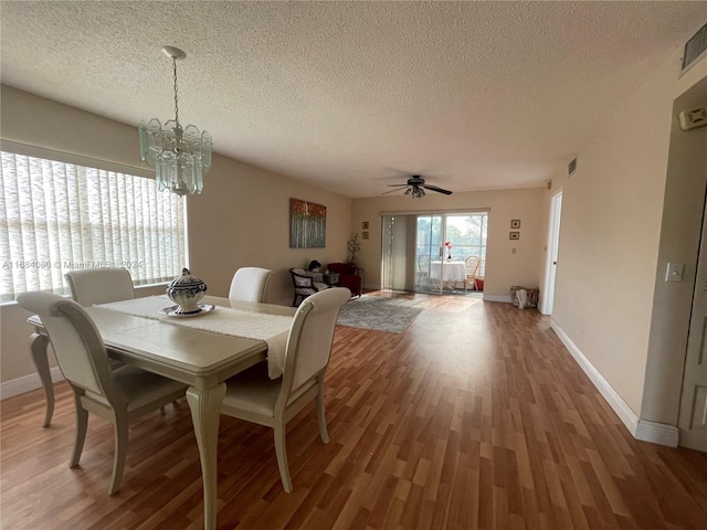 dining space with a textured ceiling, hardwood / wood-style flooring, and ceiling fan with notable chandelier