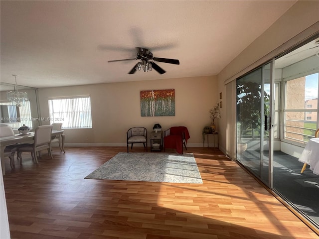 living area with a healthy amount of sunlight, hardwood / wood-style flooring, and ceiling fan with notable chandelier