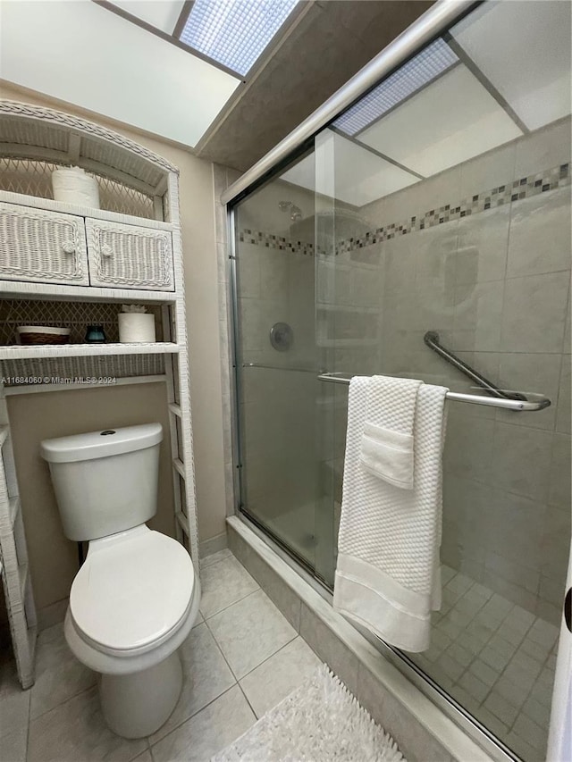 bathroom with a shower with door, toilet, and tile patterned flooring