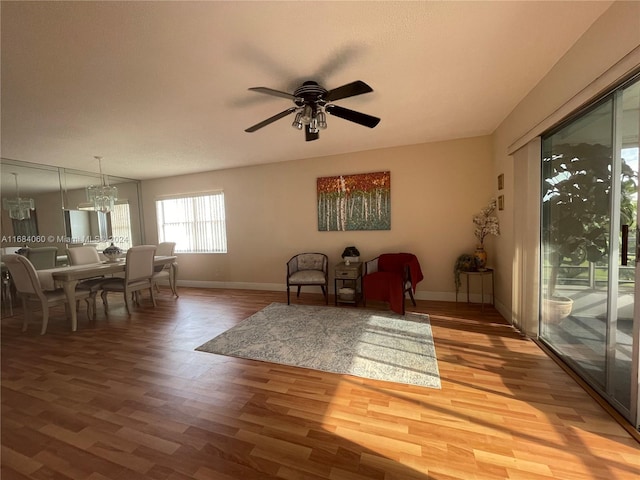 living area featuring hardwood / wood-style floors and ceiling fan with notable chandelier