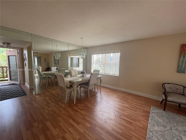 dining space featuring a textured ceiling, hardwood / wood-style flooring, and a chandelier