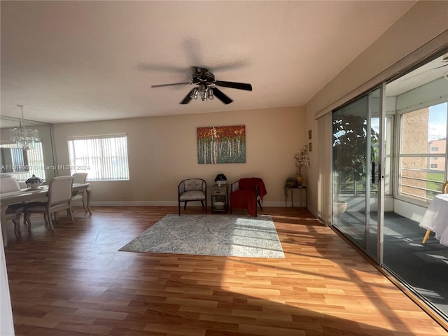 living area featuring hardwood / wood-style floors, ceiling fan with notable chandelier, and plenty of natural light