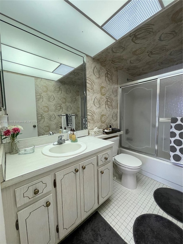 full bathroom featuring toilet, tile patterned flooring, vanity, shower / bath combination with glass door, and a skylight