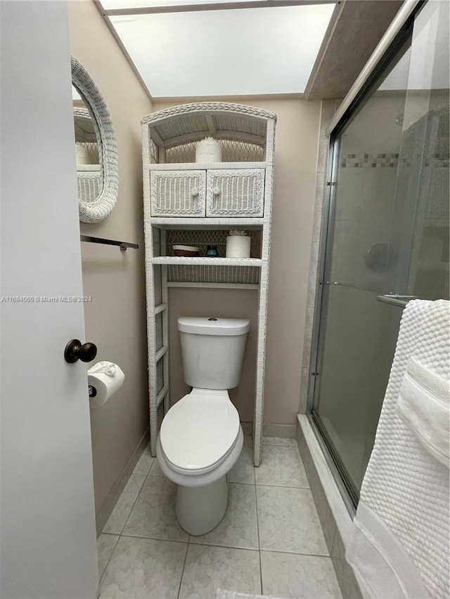 bathroom featuring toilet, tile patterned flooring, and a shower with door