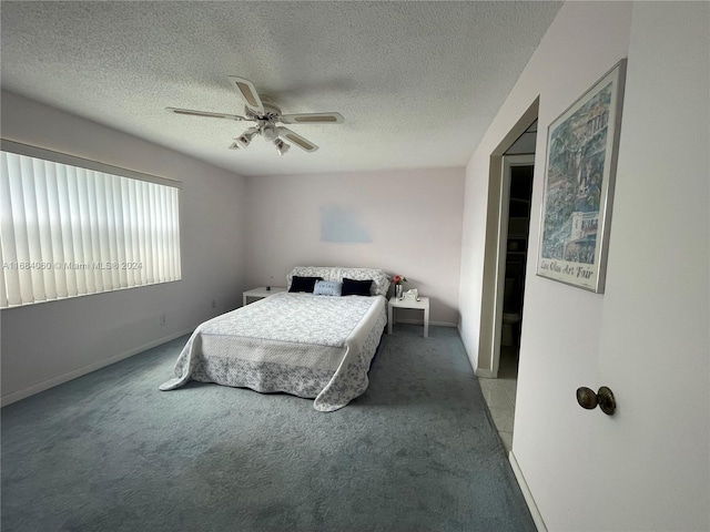 bedroom featuring dark colored carpet, a textured ceiling, and ceiling fan