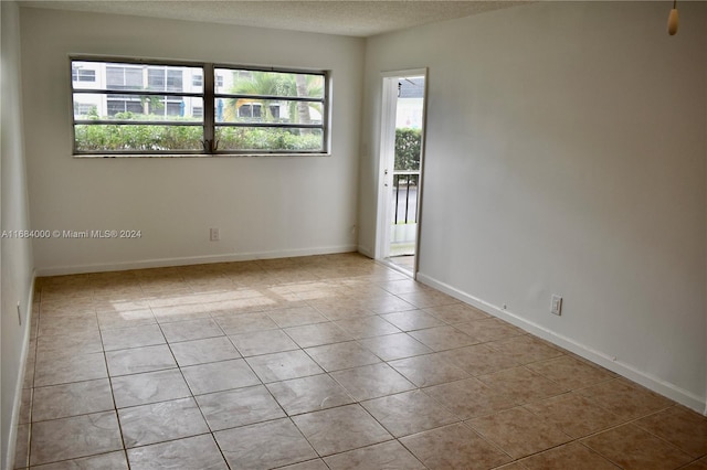 unfurnished room with a textured ceiling, light tile patterned floors, and a wealth of natural light