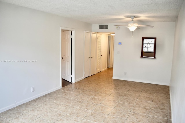 unfurnished room featuring a textured ceiling, light tile patterned flooring, and ceiling fan