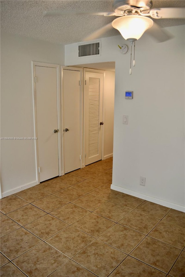 tiled empty room featuring a textured ceiling and ceiling fan