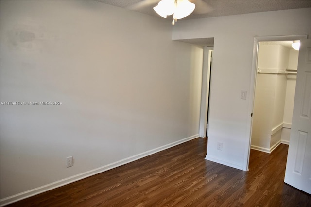 unfurnished bedroom featuring a walk in closet, dark hardwood / wood-style floors, a closet, and ceiling fan