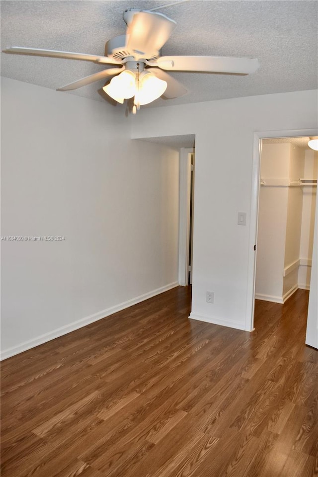 unfurnished bedroom with a textured ceiling, dark hardwood / wood-style floors, and ceiling fan