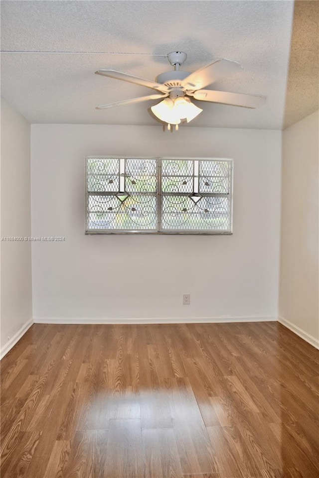 empty room featuring ceiling fan, hardwood / wood-style flooring, and a textured ceiling