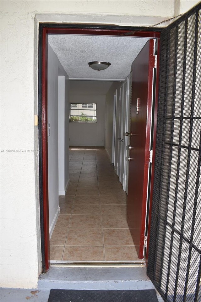 hallway with a textured ceiling and tile patterned floors