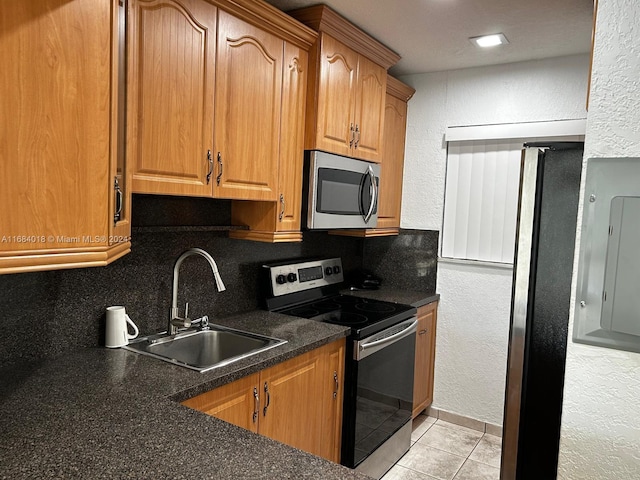 kitchen with appliances with stainless steel finishes, light tile patterned flooring, decorative backsplash, and sink