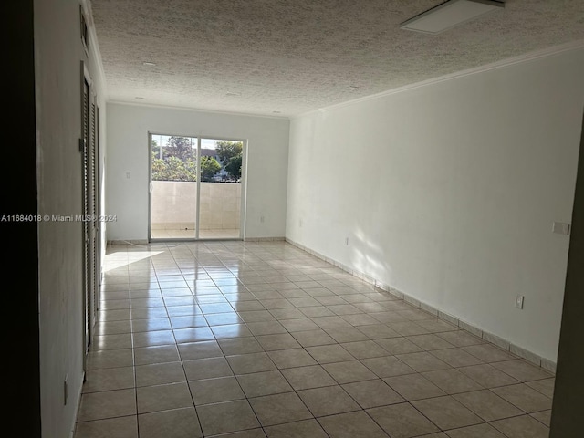 tiled spare room featuring ornamental molding and a textured ceiling