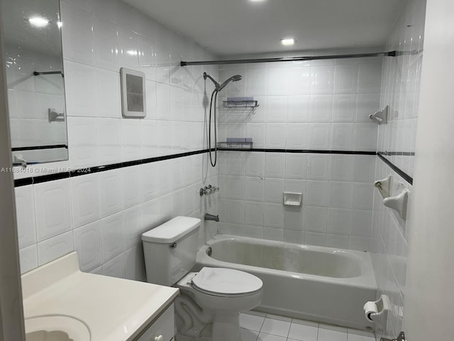 full bathroom with vanity, toilet, tiled shower / bath combo, and tile walls