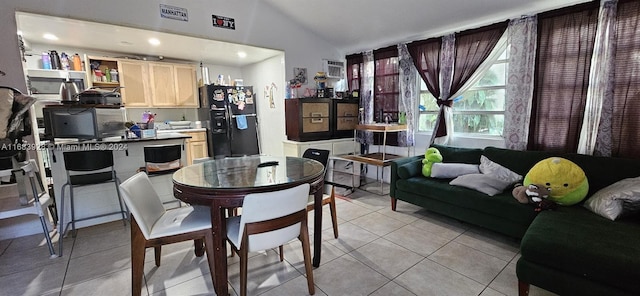 dining space with light tile patterned floors and vaulted ceiling