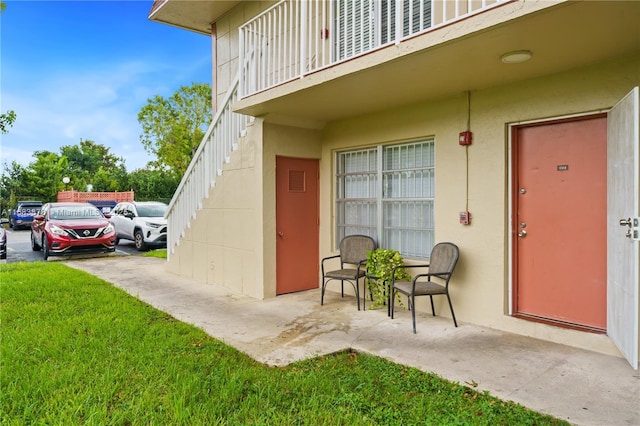 doorway to property with a balcony and a yard