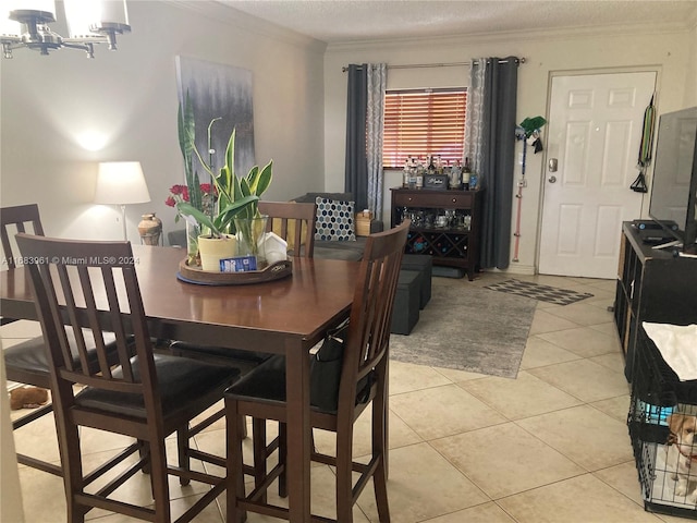 tiled dining room featuring a textured ceiling, crown molding, and an inviting chandelier