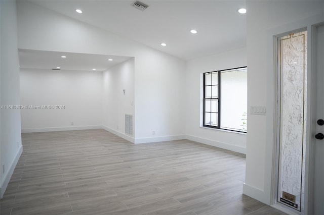 spare room with light hardwood / wood-style flooring and vaulted ceiling