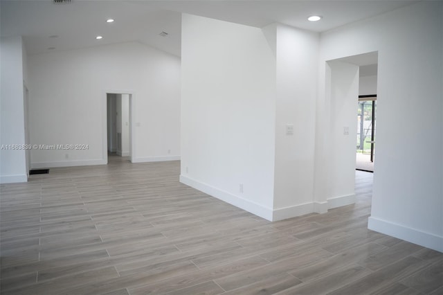 empty room with vaulted ceiling and light wood-type flooring