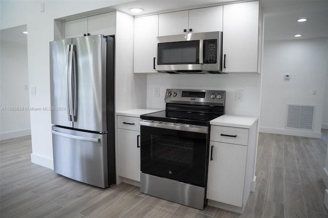 kitchen with white cabinets, stainless steel appliances, and light hardwood / wood-style floors