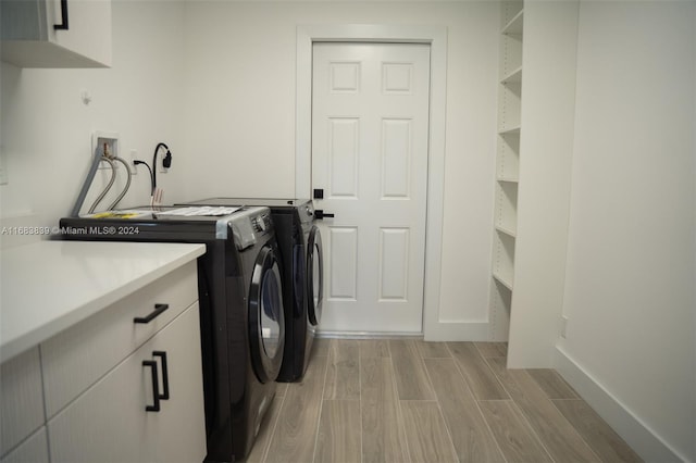 laundry room featuring cabinets, light hardwood / wood-style flooring, and washer and dryer