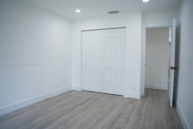 unfurnished bedroom with a closet and light wood-type flooring