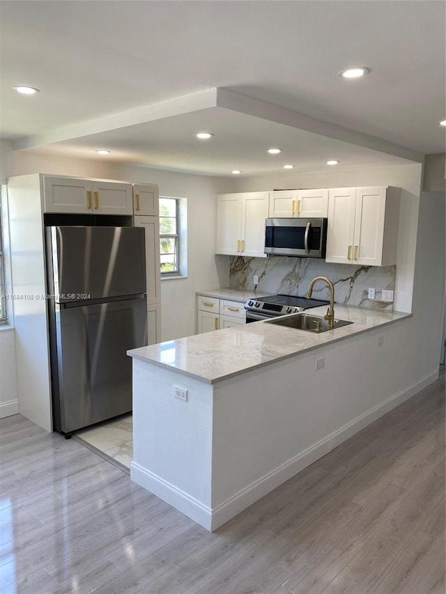 kitchen with kitchen peninsula, white cabinetry, light hardwood / wood-style flooring, and appliances with stainless steel finishes