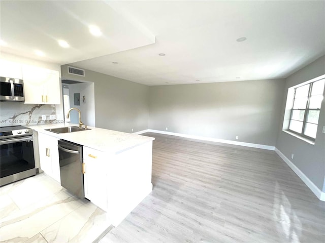 kitchen featuring stainless steel appliances, light wood-type flooring, decorative backsplash, sink, and white cabinets