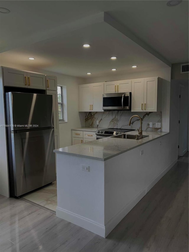 kitchen featuring stainless steel appliances, light hardwood / wood-style floors, white cabinetry, and kitchen peninsula