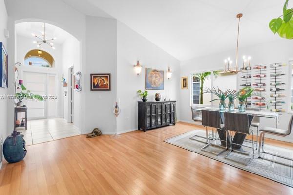 entryway with an inviting chandelier, light hardwood / wood-style flooring, and high vaulted ceiling