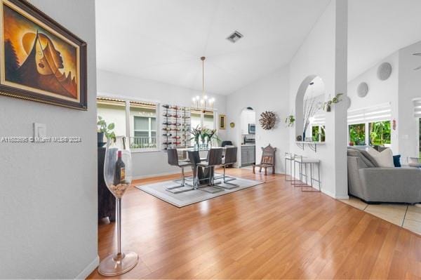 dining room with hardwood / wood-style floors, a chandelier, high vaulted ceiling, and a wealth of natural light