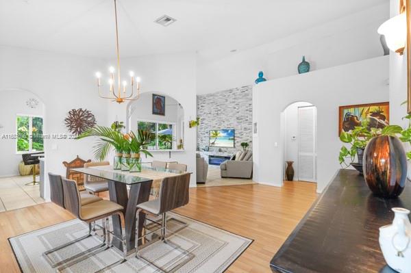 dining space with a wealth of natural light, an inviting chandelier, wood-type flooring, and a towering ceiling