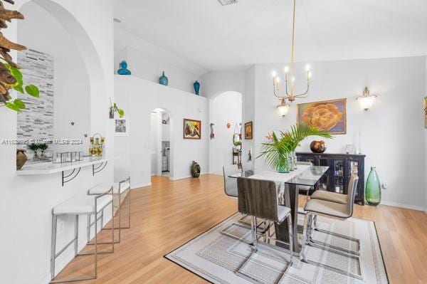 dining area featuring light hardwood / wood-style flooring, a notable chandelier, and lofted ceiling