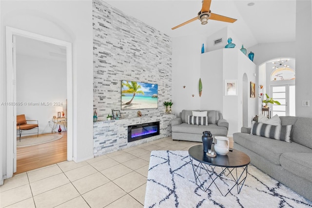 living room with light tile patterned flooring, ceiling fan with notable chandelier, and high vaulted ceiling