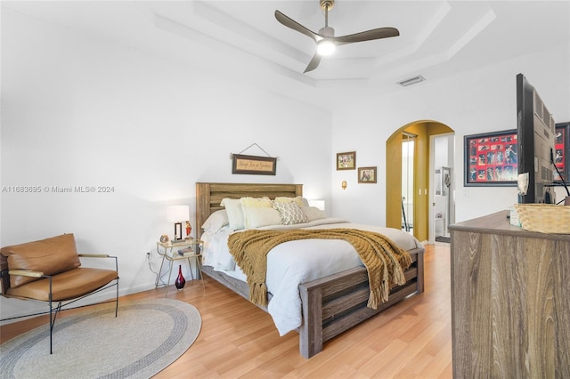 bedroom featuring a tray ceiling, light hardwood / wood-style floors, and ceiling fan