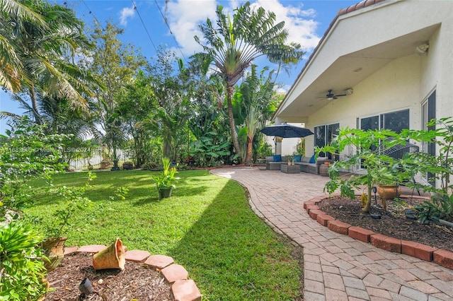 view of yard with an outdoor living space, a patio, and ceiling fan