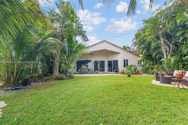 back of house with a patio area, ceiling fan, a lawn, and an outdoor living space