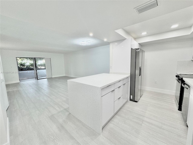 kitchen with stainless steel fridge, white cabinets, and light wood-type flooring