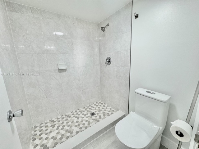 bathroom with a tile shower and toilet