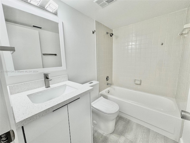 full bathroom with toilet, tiled shower / bath combo, hardwood / wood-style flooring, and vanity