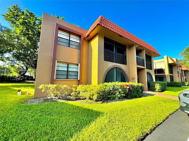 view of front of house with a balcony and a front lawn