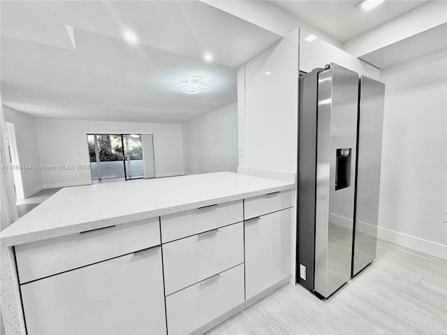 kitchen with stainless steel refrigerator with ice dispenser, light hardwood / wood-style flooring, and white cabinets