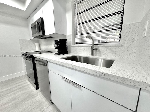 kitchen featuring decorative backsplash, white cabinets, sink, light hardwood / wood-style floors, and stainless steel appliances