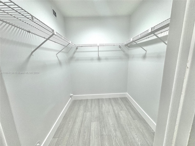 walk in closet with light hardwood / wood-style floors