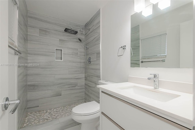 bathroom with vanity, toilet, and tiled shower