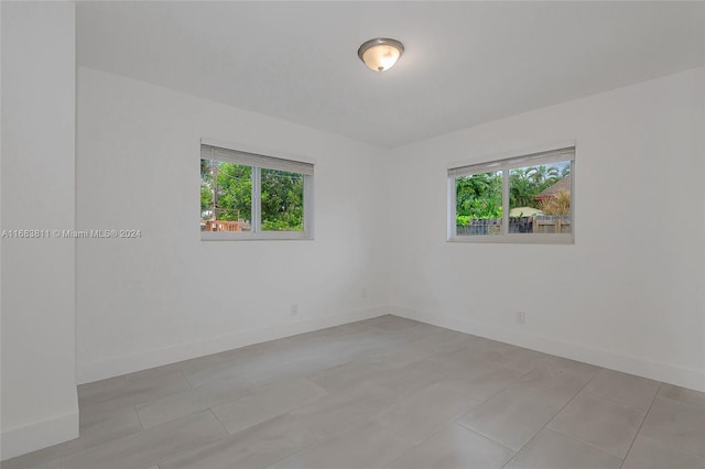 spare room featuring light tile patterned floors and plenty of natural light