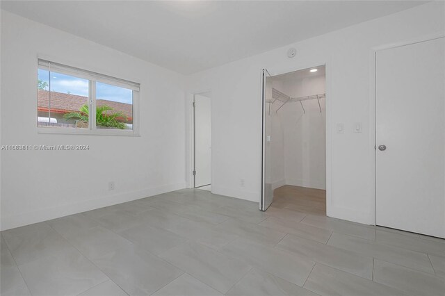 unfurnished bedroom featuring a closet, a spacious closet, and light tile patterned floors