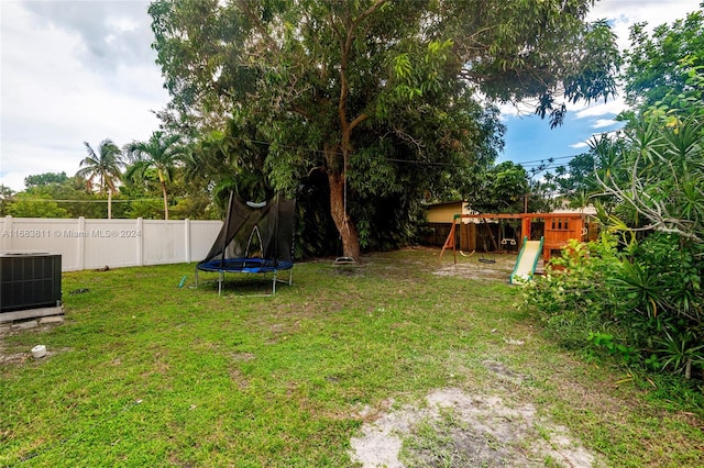 view of yard featuring a playground, central AC unit, and a trampoline