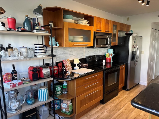 kitchen with light hardwood / wood-style floors, stainless steel appliances, and backsplash